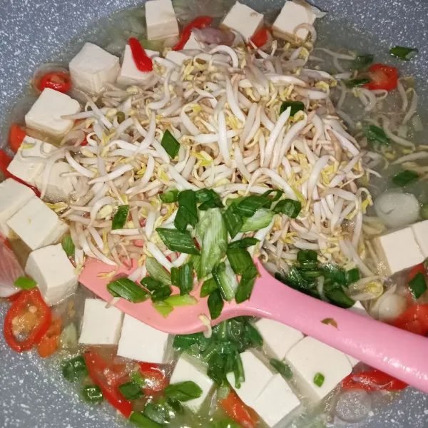 Masukkan tauge dan irisan bawang daun, lalu tambahkan gula, garam, dan kaldu jamur. Kemudian aduk rata.
