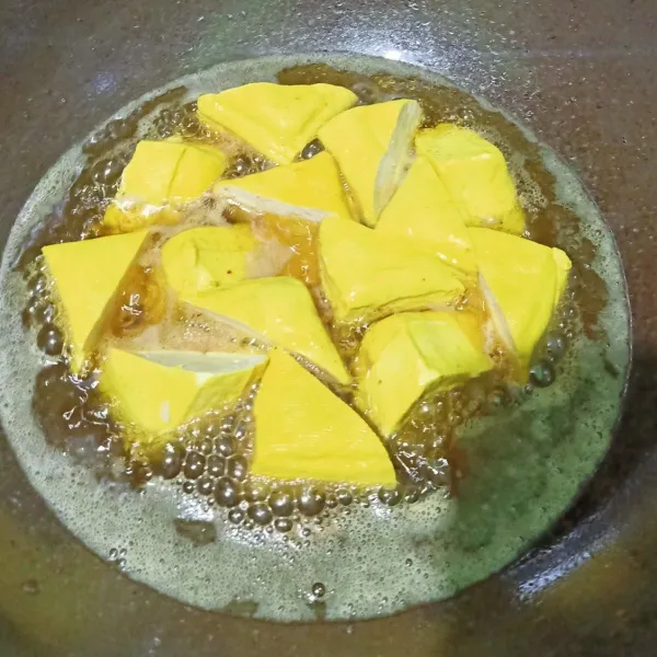 Tahu kuning berbentuk kotak potong 2 menjadi berbentuk segitiga. Lalu siapkan wajan berisikan minyak lalu goreng tahu sampai matang.