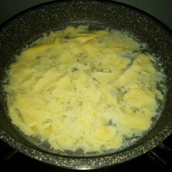 Rebus 200 ml air sampai mendidih. Tuang kocokan telur, aduk ringan. Setelah telur memadat tuangkan ke atas saringan. Biarkan tiris.