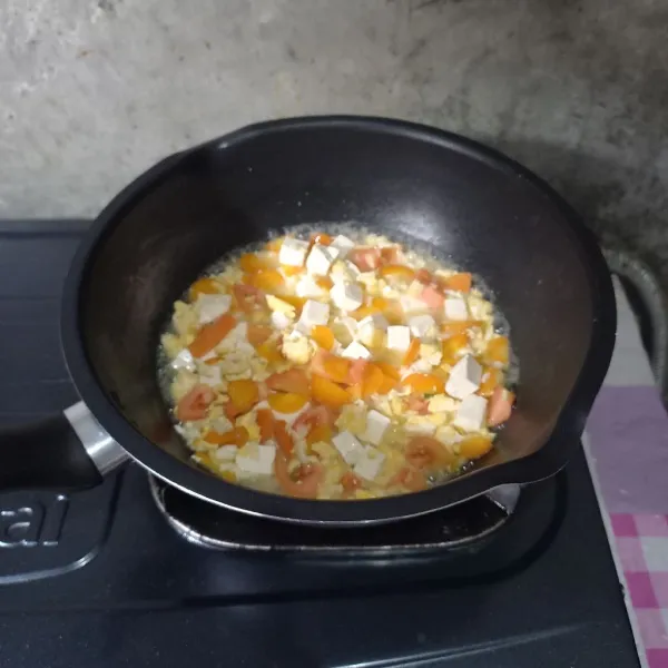 Masukkan wortel dan air. Masak sampai wortel setengah matang. Kemudian masukkan tomat dan tahu. Masak sampai layu.