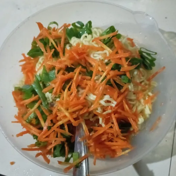 Masukkan mie, wortel, dan daun bawang, lalu aduk rata.