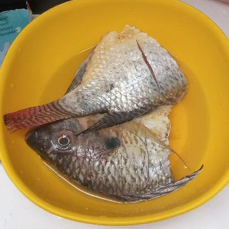 Siapkan ikan nila. Kucuri dengan air perasan jeruk nipis. Diamkan 10 menitan, lalu bilas sampai bersih.