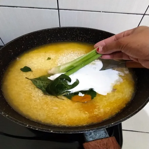 Cuci bersih beras, lalu masukkan ke dalam panci bersama dengan air, santan, garam, daun jeruk, daun salam dan serai.