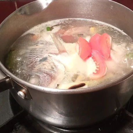 Setelah ikan matang, tambahkan irisan tomat.