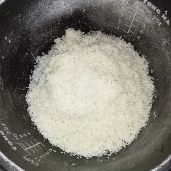 Cuci beras sampai bersih, lalu masukkan ke dalam rice cooker.
