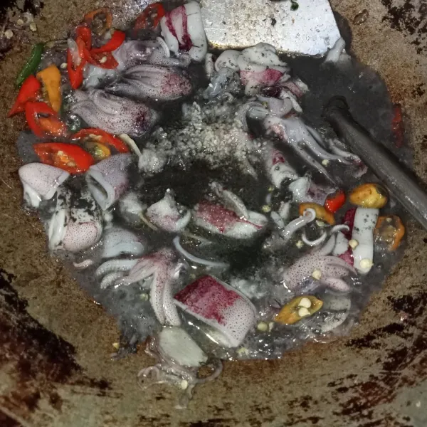 Masukkan cumi beserta air tintanya, ke dalam wajan, aduk rata lalu tambahkan air, gula, garam dan kaldu jamur.
