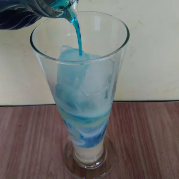 Tuangkan sirup biru ke dalam gelas.