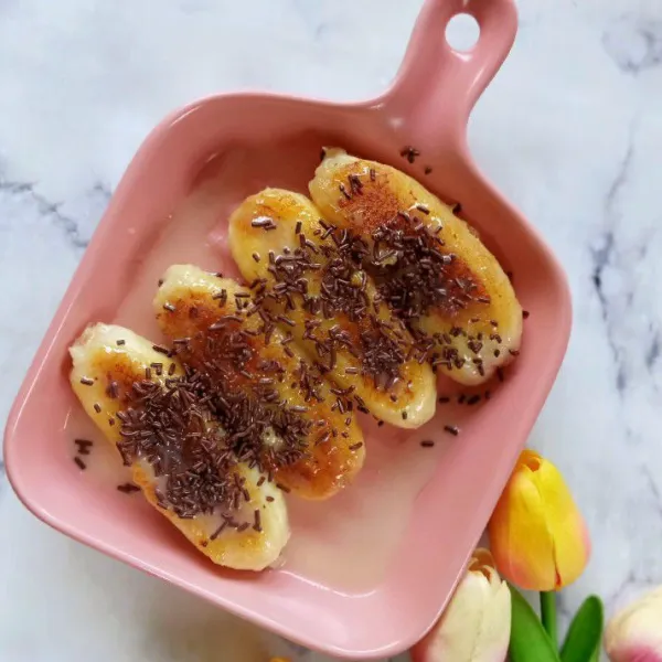 Tambahkan topping cokelat di atas pisang. Pisang panggang cokelat susu siap dinikmati.