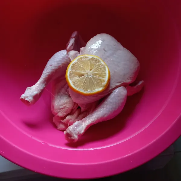 Bersihkan ayam, potong kepala dan kaki ayam, lumuri perasan lemon.