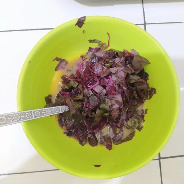 Tambahkan irisan bayam merah, kaldu bubuk dan lada bubuk lalu aduk rata.