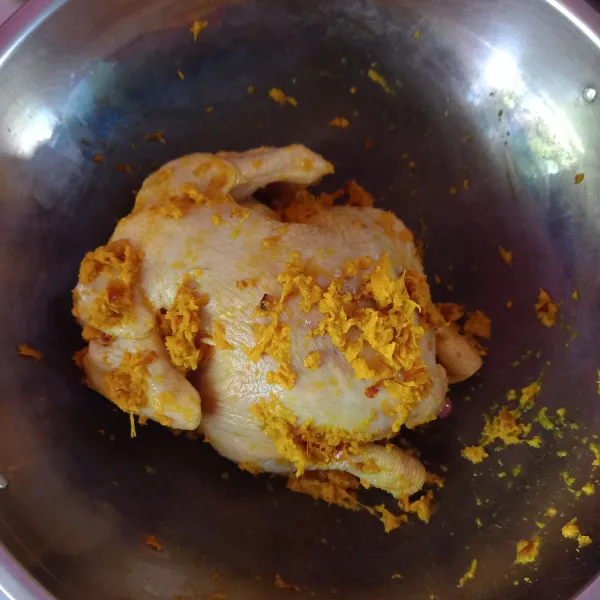 Taruh ayam di atas wajan, lumuri bumbu halus merata sampai ke dalam perut ayam, diamkan selama 30 menit.