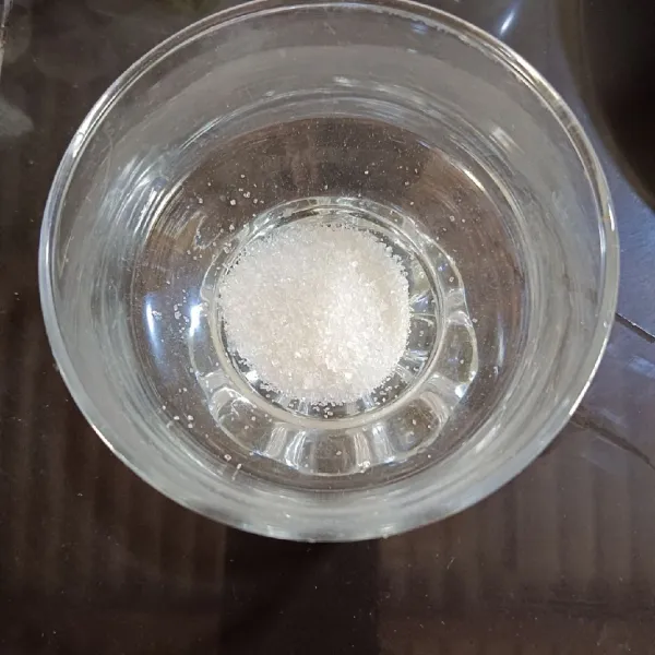Tuang gula pasir dalam gelas.
