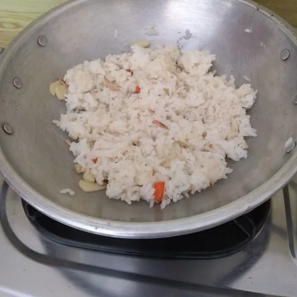Masukkan nasi ke wajan (gunakan api kompor kecil), lalu aduk.