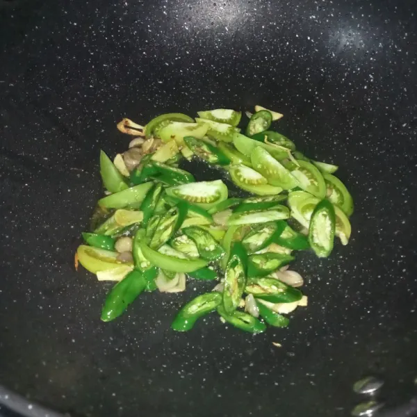Masukkan irisan cabai hijau dan tomat, lalu aduk-aduk sampai layu.