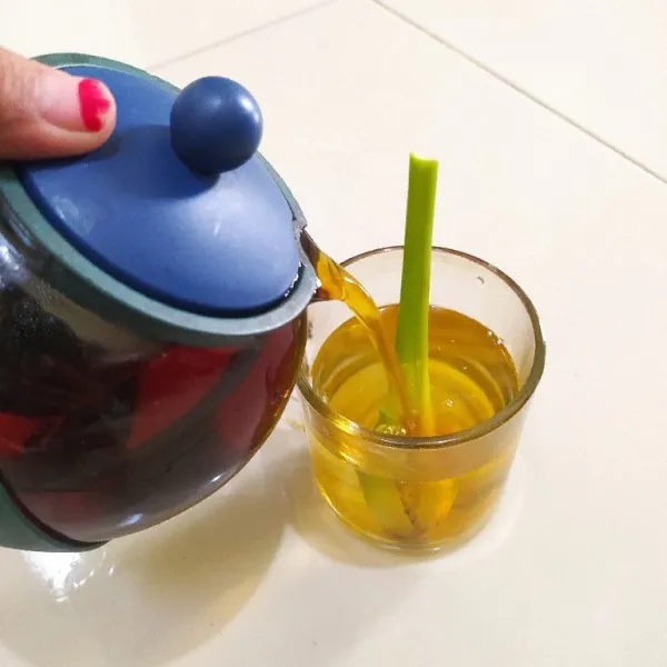 Tuang air rebusan serai ke dalam gelas lalu tambahkan air teh yang tadi diseduh.