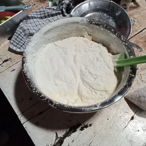 Sambil diayak masukkan tepung terigu, baking powder. 
Mixer dengan kecepatan rendah hingga tercampur. 
Tambahkan kelapa parut, aduk dengan spatula hingga tercampur.