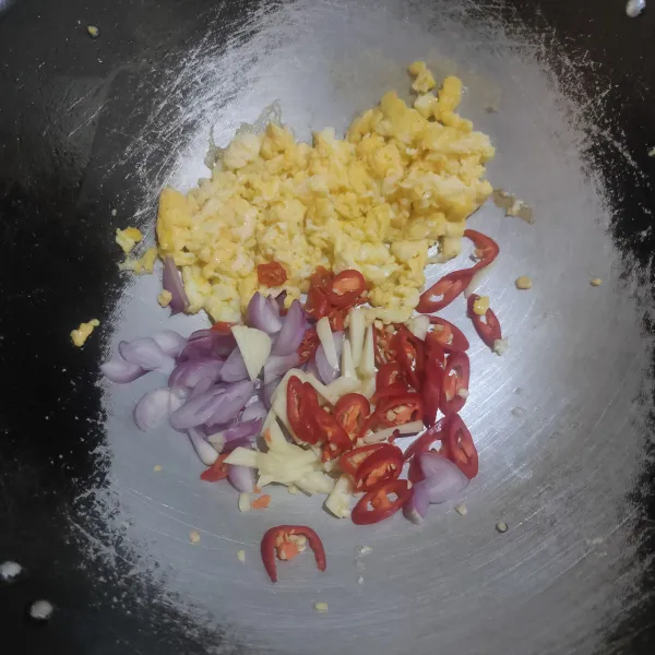 Sisihkan telur, lalu masukkan irisan cabai rawit, cabai merah, bawang putih, dan bawang merah. Tumis hingga harum.