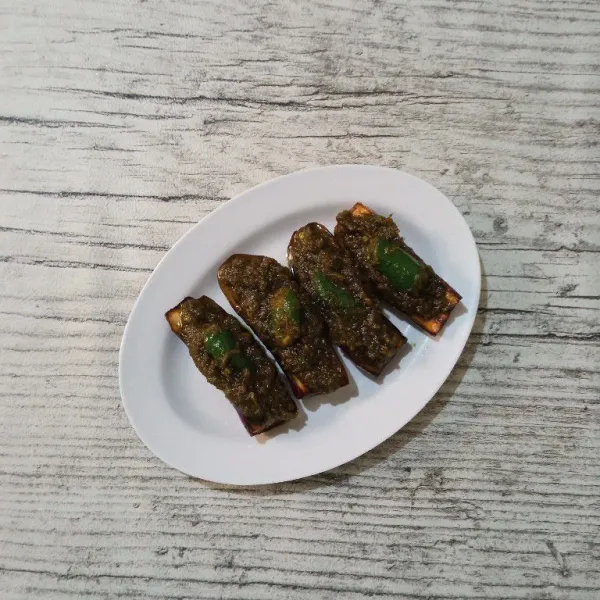 Tata terong di atas piring saji, lalu tambahkan sambal hijau di atas terong. Kemudian taburi dengan ikan teri goreng.