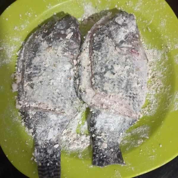 Lumuri ikan dengan perasan lemon cui, lalu baluri ikan dengan tepung bumbu sampai rata.