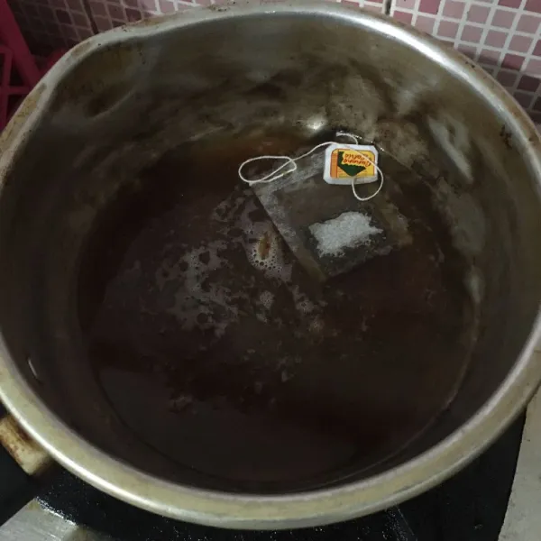 Rebus kembali, lalu masukkan gula merah, teh celup dan gula pasir, aduk rata dan biarkan mendidih dan gula larut. Sisihkan, tunggu dingin.