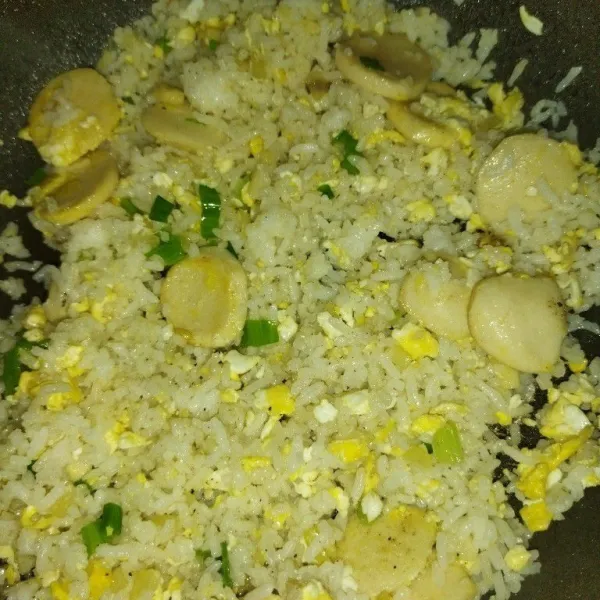 Masak nasi hingga agak kering, lalu masukkan daun bawang yang berwarna hijau dan aduk rata. Kemudian angkat dan sajikan.