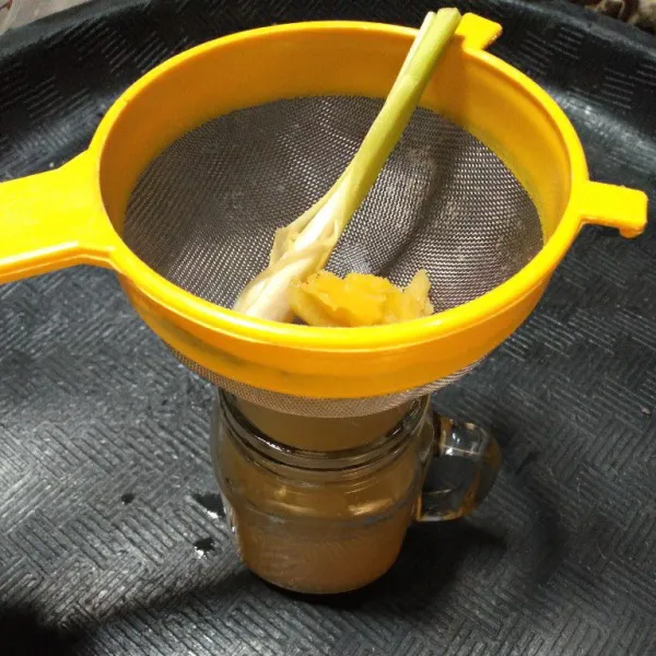 Tuang air rebusan jahe ke dalam gelas sambil di saring.