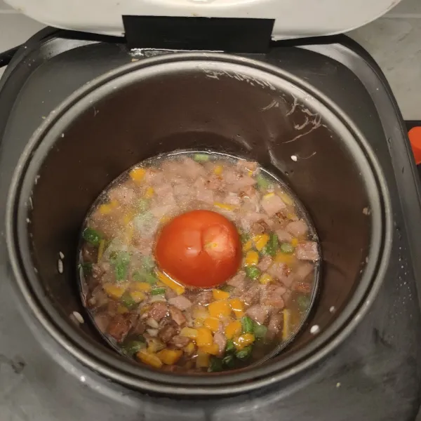 Masukkan bahan yang di oseng tadi dan kaldu jamur ke wadah beras, lalu tambahkan tomat di tengahnya.