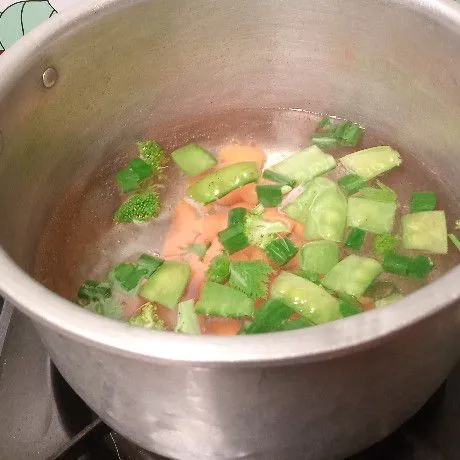 Rebus irisan bawang merah dan bawang putih di air. Kemudian masukkan sayuran.