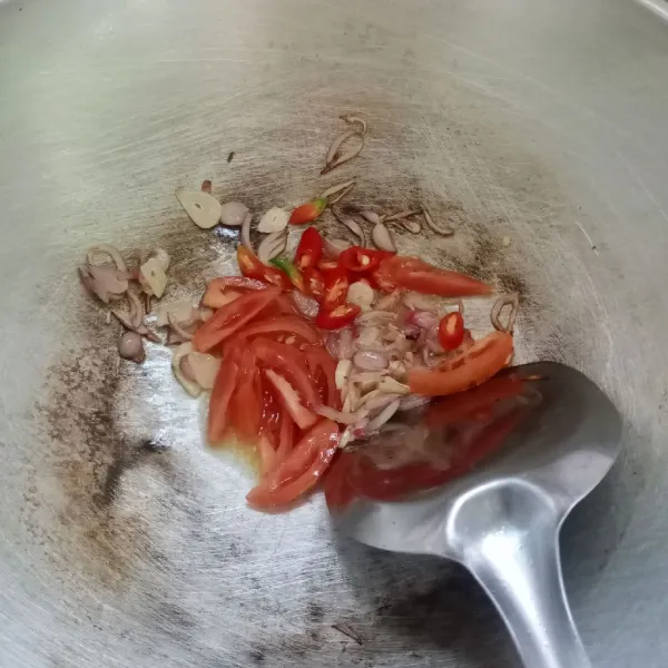 Masukkan irisan cabai dan tomat, kemudian tumis sampai layu.