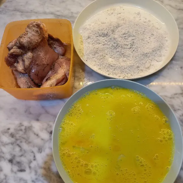 Siapkan tepung dan telur. 
Baluri ayam yang sudah dimarinasi dengan lapisan telur kocok dan tepung pelapis.