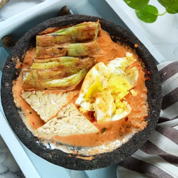 Masukkan terong bakar telur rebus dan tempe rebus ke dalam sambal sambil sedikit di penyet. Sambal santan siap disajikan.