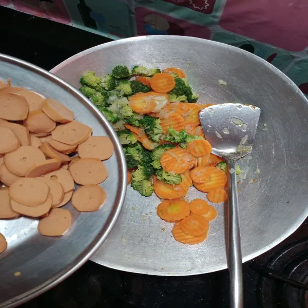 Masukkan juga sosis, lalu masukkan sedikit air, tutup wajan, masak sekitar 5 menit, kemudian bumbui dengan garam dan penyedap rasa, cek rasa.