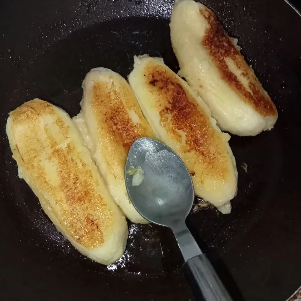 Balik pisang jika sudah mulai berubah warna, sedikit ditekan pisang menggunakan sendok supaya seluruh permukaan pisang matang merata.