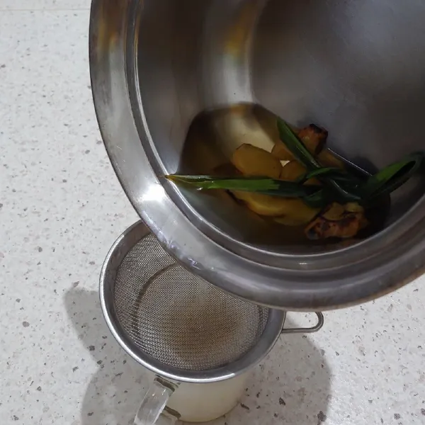 Saring air rebusan jahe dan pandan ke dalam gelas saji.
