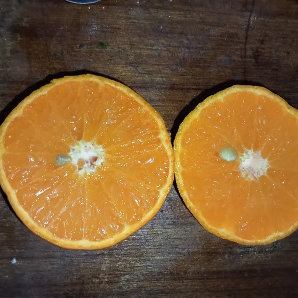 Cuci bersih jeruk kemudian potong menjadi dua bagian.