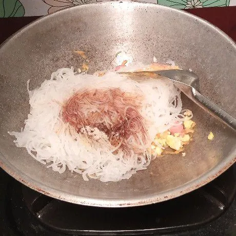 Masukkan bihun jagung, kecap manis, garam, kaldu bubuk, merica. Aduk lagi.