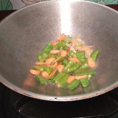 Tuang sedikit air, lalu masukkan sayuran dan aduk rata. Masak sampai sayuran agak empuk.