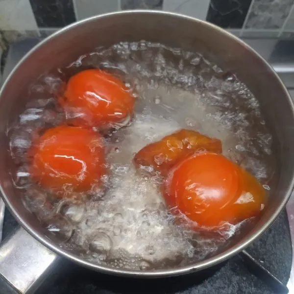 Rebus tomat dan air sampai mendidih serta kulit tomat mulai terkelupas, lalu matikan kompor.