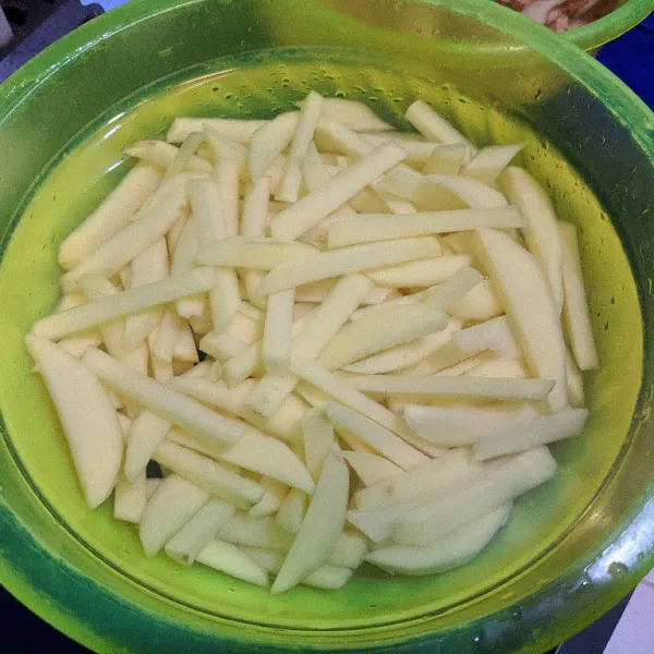 Potong memanjang kentang yang telah di kupas. Cuci bersih kentang stik hingga air cucian bening dan tambahkan secukupnya garam, lalu rendam kentang dalam air garam selama minimal 15 menit.