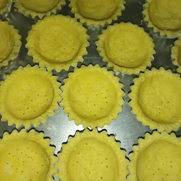 Siapkan cetakan pie, lalu oles cetakan dengan margarin, lalu cetak adonan di atas cetakan pie, tusuk-tusuk bagian tengah pie.