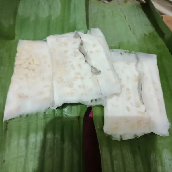 Siapkan tempe yang dibungkus daun pisang.