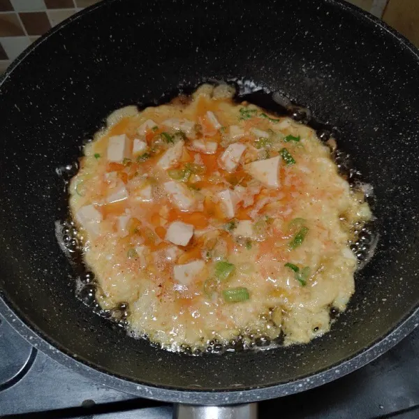 Panaskan wajan, beri minyak goreng. Lalu masukan kocokan tahu telur, biarkan bawahnya berubah kecokelatan sebelum dibalik agar telur tidak hancur.
