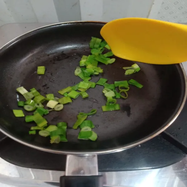Siapkan teflon, beri minyak goreng secukupnya, masukkan daun bawang, tumis hingga layu.