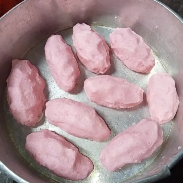 Ambil adonan singkong secukupnya dan isi dengan pisang, lalu bentuk lonjong. Tata di loyang yang sudah dioles tipis dengan minyak goreng.