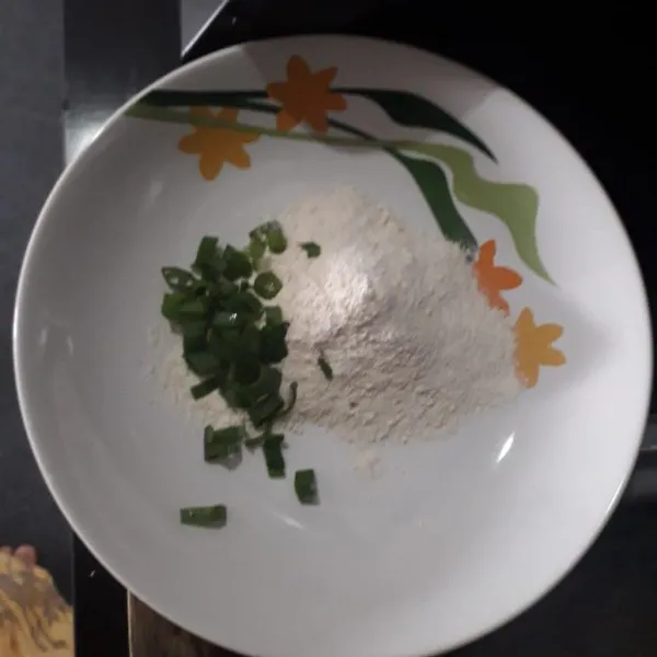 Masukkan tepung serba guna dan daun bawang ke dalam mangkuk.