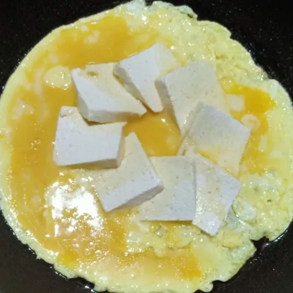 Setelah tahu setengah matang tuangkan telur diatasnya, tutup teflonnya dan masak hingga telur matang.