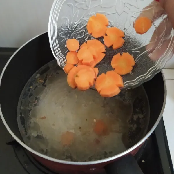 Tumis bawang putih sampai harum lalu masukkan 500 ml air dan 1 buah kaldu blok. Aduk rata, masukkan wortel. Masak hingga air mendidih.