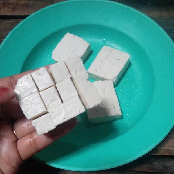 Potong tahu menjadi 2 bagian, kemudian kerat tahu tapi jangan sampai putus.