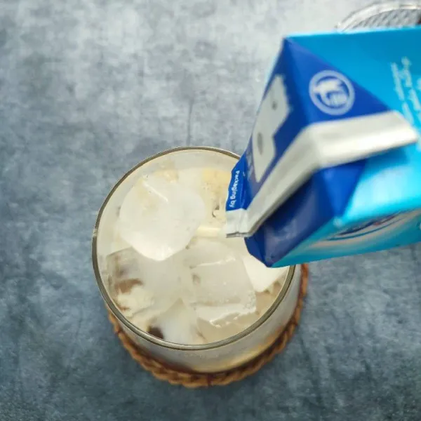 Tambahkan susu full cream sampai ¾ tinggi gelas.