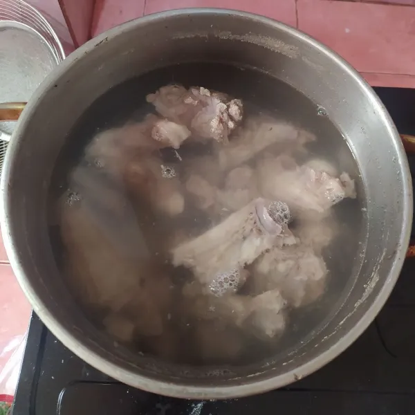 Rebus air hingga mendidih, lalu masukkan daging kambing. Kecilkan apinya, Dan buang busa-busa yang mengambang. Potong daging bite size.